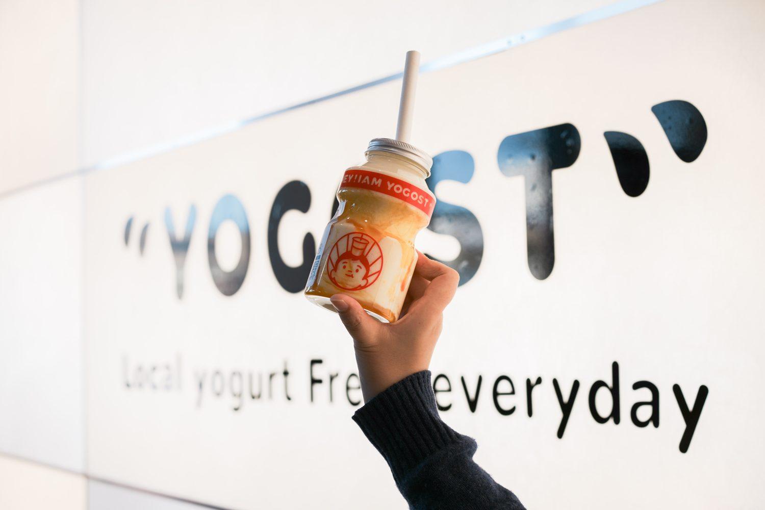 A bottle of Yogost held in front of the Edmonton store wall