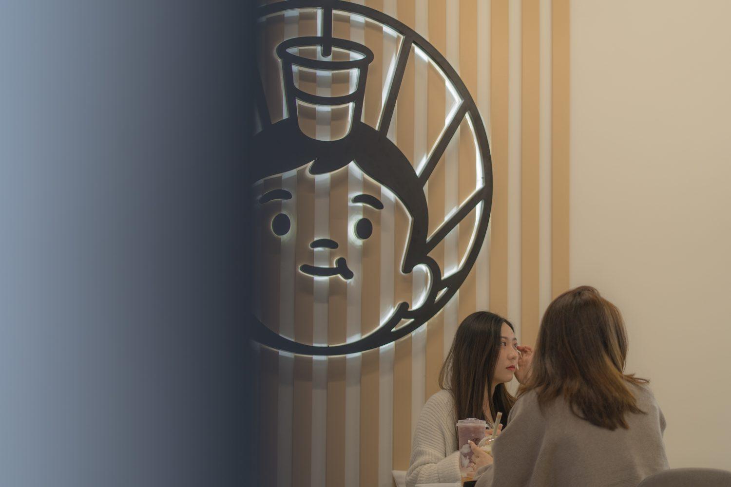 Customers sitting beneath the glowing Yogost character sign